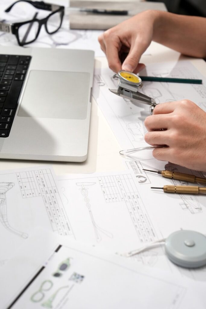 Engineer measuring a component with a dial caliper over technical drawings
