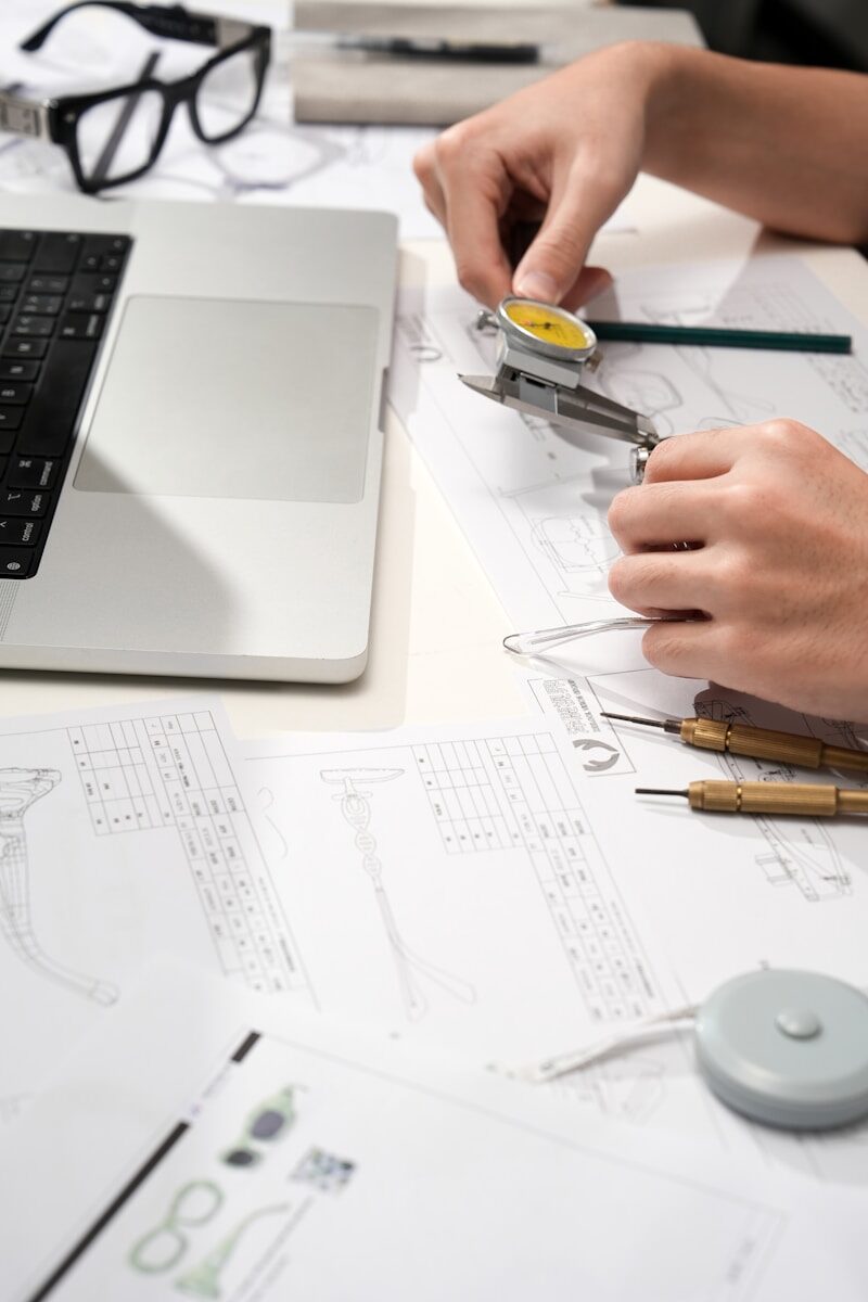 Engineer measuring a component with a dial caliper over technical drawings