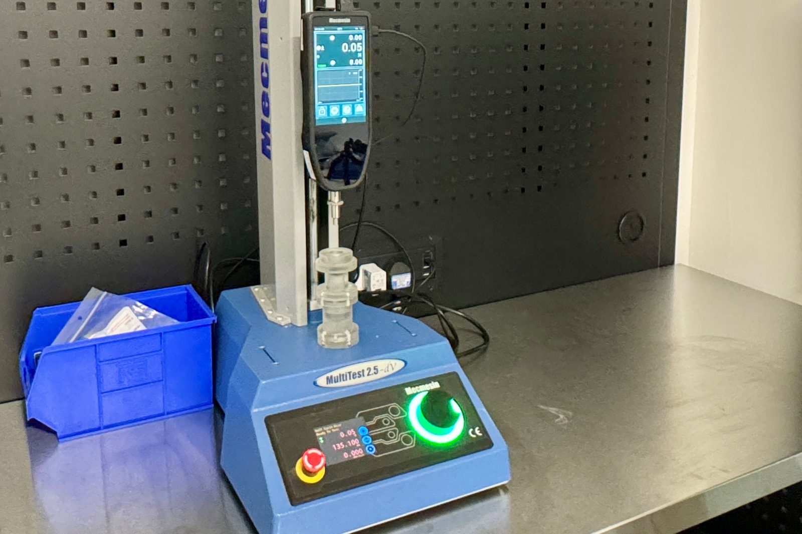Mecmesin MultiTest 2.5-dV motorised force tester on the bench in the MDIN workshop, with a device component in the test fixture