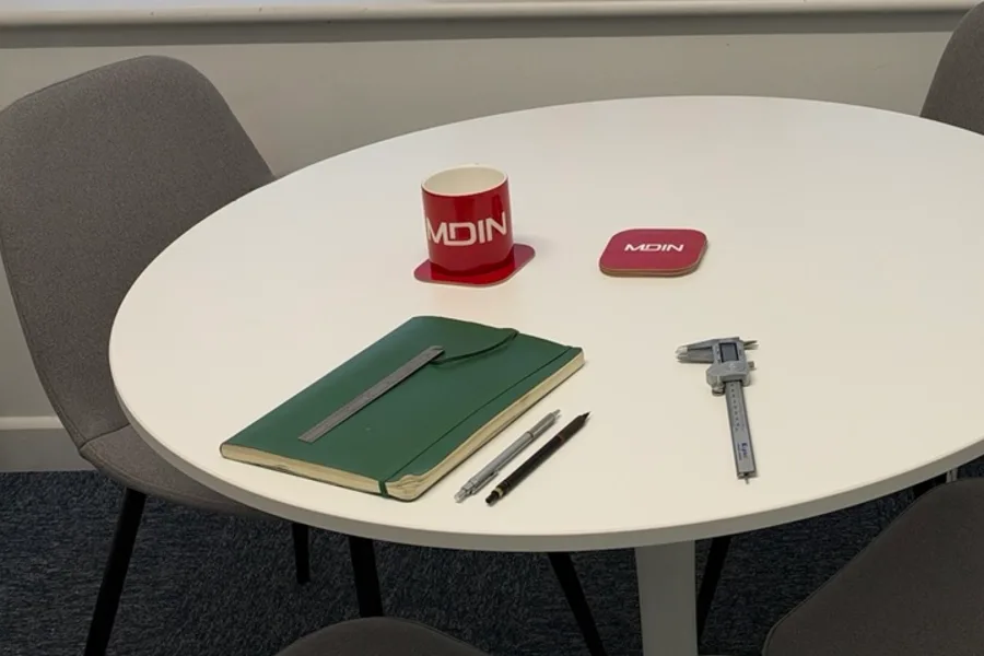 Meeting table with notebook, callipers and MDIN mug in the MDIN meeting room