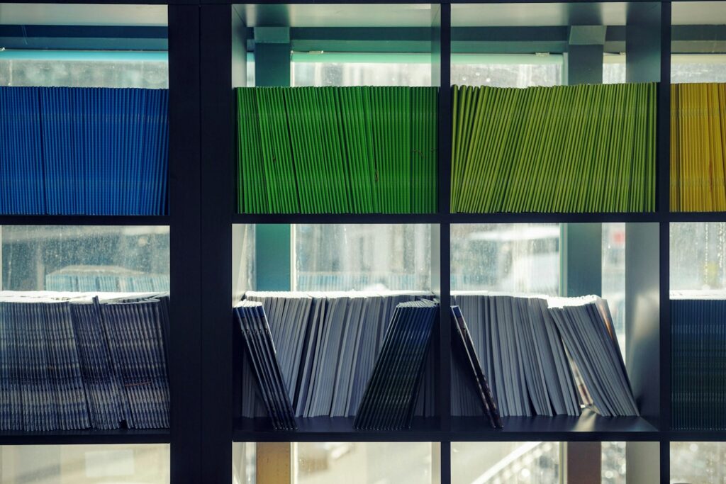 Colour-coded bound documents arranged on shelves, illustrating the technical file template post